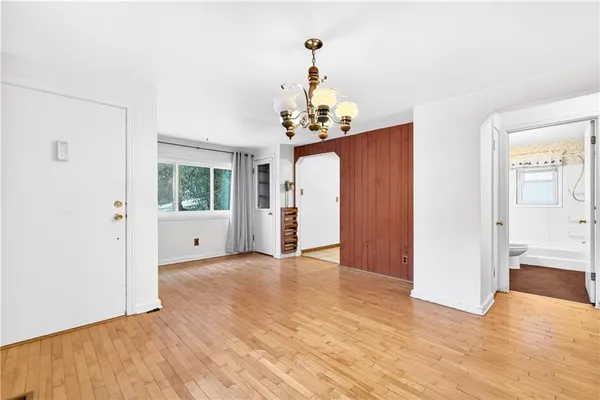 a view of a hallway with wooden floor and a bathroom