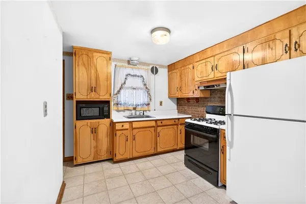 a kitchen with granite countertop a refrigerator a sink and wooden floors