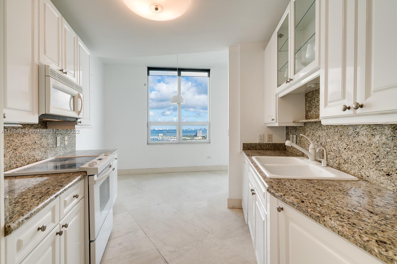 848 Brickell Key Drive, Unit 4002 Miami, FL 33131 - Photo 7 of 19 a kitchen with granite countertop a sink stove and cabinets