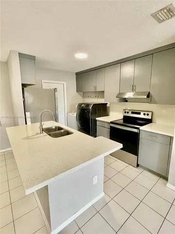 a kitchen with stainless steel appliances a sink a stove a microwave and cabinets