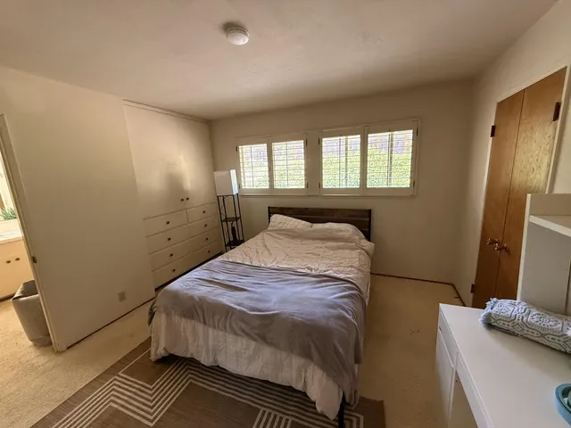 a bed sitting in a spacious bedroom next to a window