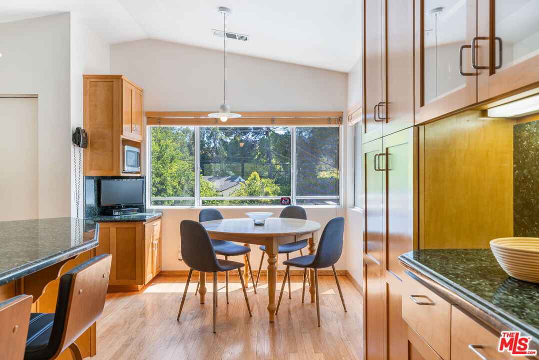 2860 Roscomare Road Los Angeles, CA 90077 - Photo 6 of 15 a dining room with stainless steel appliances granite countertop a stove top oven a dining table and chairs with wooden floor
