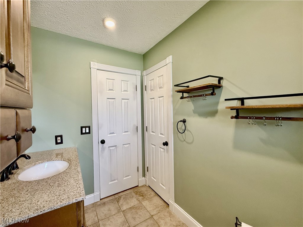 2900 Shellhart Road Barberton, OH 44203 - Photo 12 of 44 Bathroom with a textured ceiling, vanity, light tile patterned floors, and recessed lighting