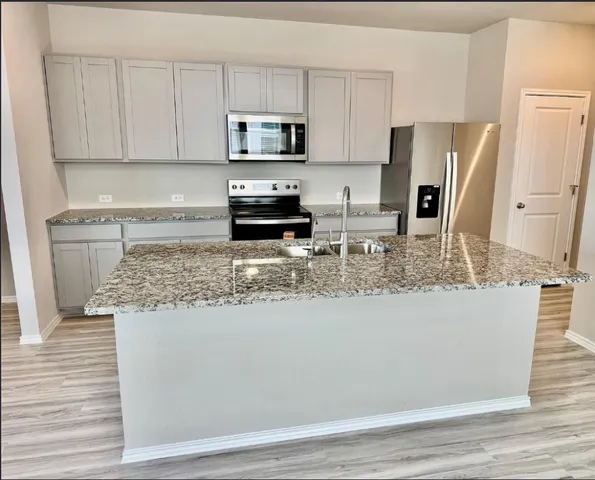 a kitchen with stainless steel appliances granite countertop a refrigerator a stove top oven a sink and dishwasher