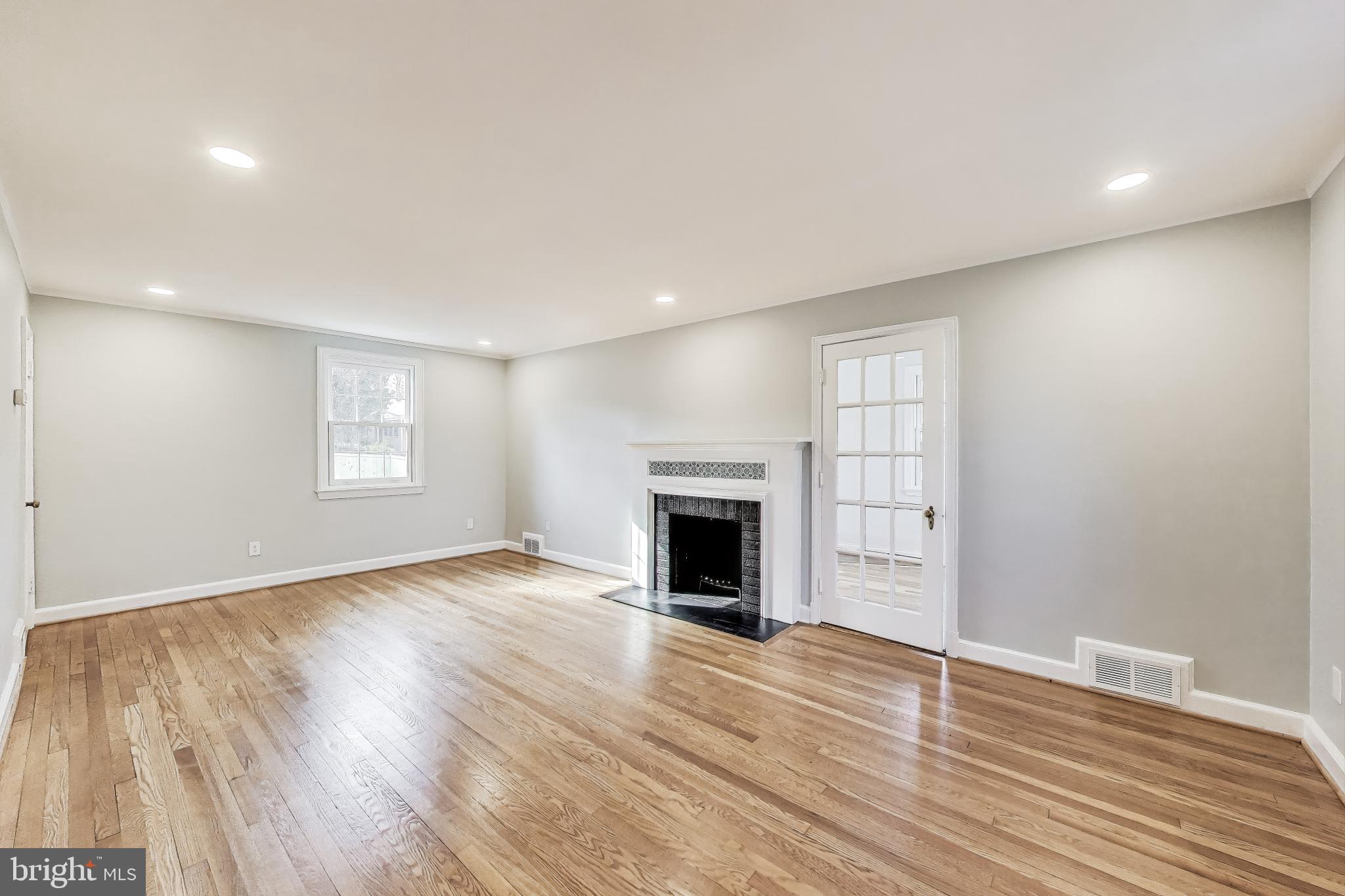 9312 Walden Road Silver Spring, MD 20901 - Photo 7 of 41 a view of an empty room with wooden floor fireplace and a window