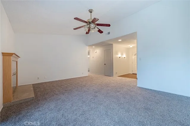 an empty room with a chandelier fan and windows