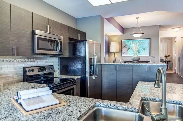 a kitchen with stainless steel appliances granite countertop a refrigerator a stove top oven a sink dishwasher and granite countertops with cabinets