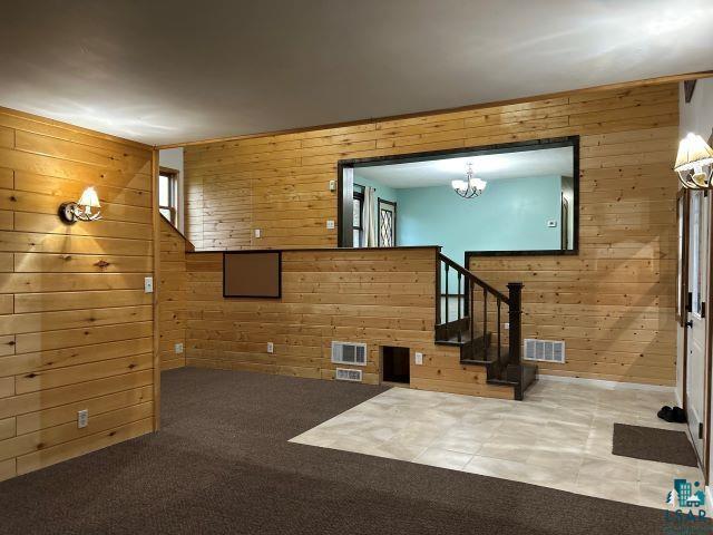 8353 Mannik Road Iron River, WI 54847 - Photo 32 of 48 Entryway with wooden walls, stairway, carpet floors, and a chandelier