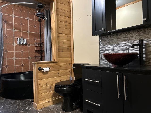 8353 Mannik Road Iron River, WI 54847 - Photo 35 of 48 Bathroom with vanity, shower / bath combination with curtain, tasteful backsplash, and dark tile patterned floors