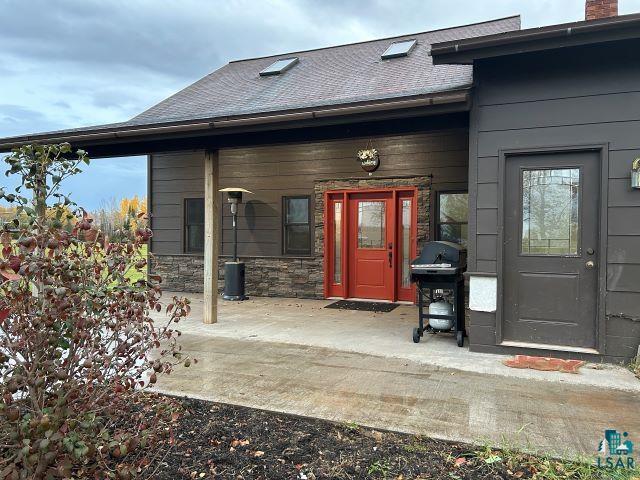 8353 Mannik Road Iron River, WI 54847 - Photo 45 of 48 Doorway to property featuring a shingled roof, stone siding, and a chimney