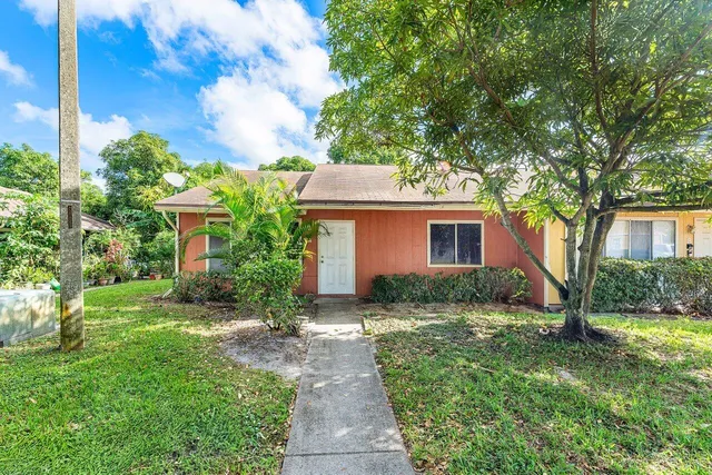 a view of a house with a yard and large tree