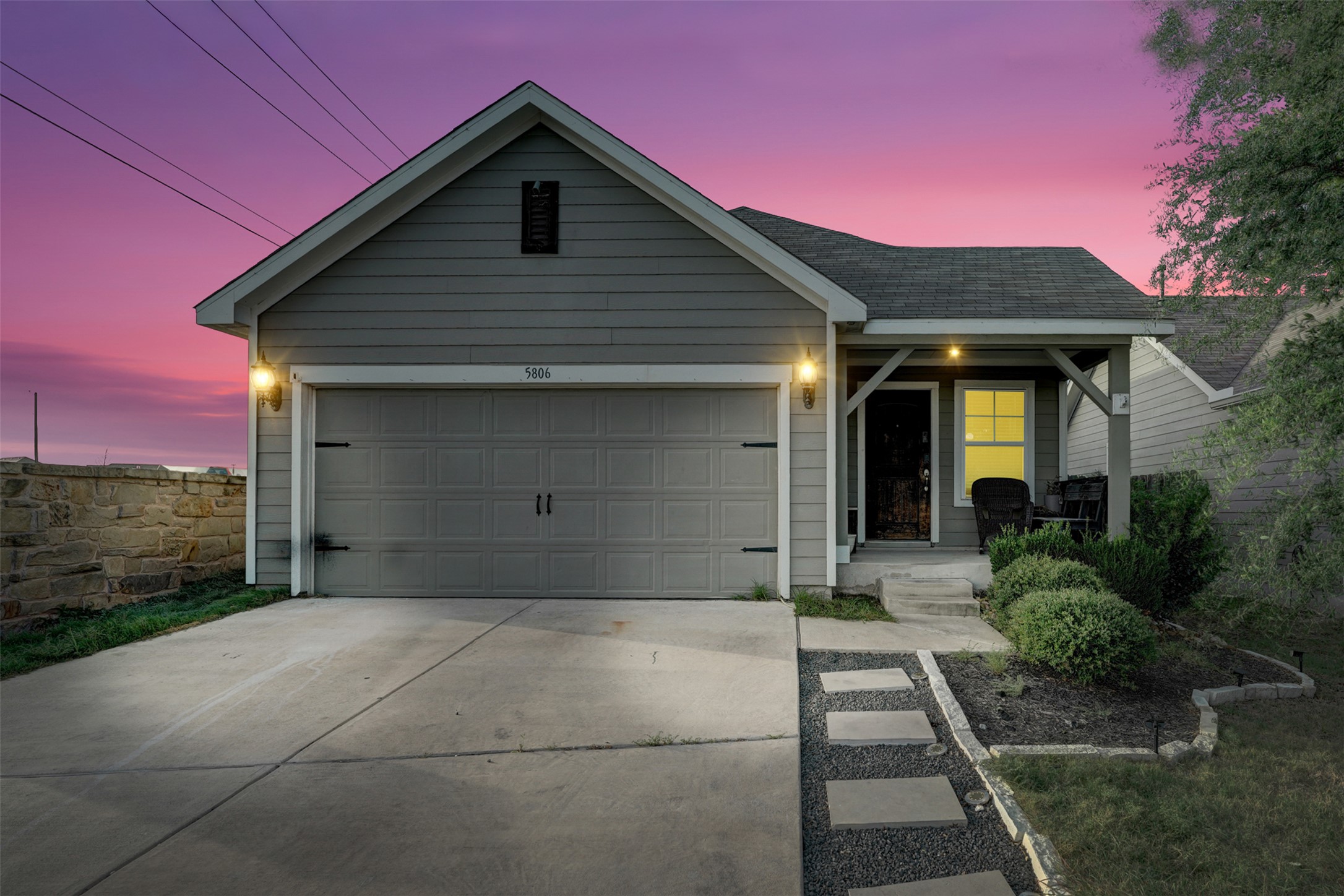 A welcoming facade, blending stone and siding, offers inviting curb appeal under an evening sky.