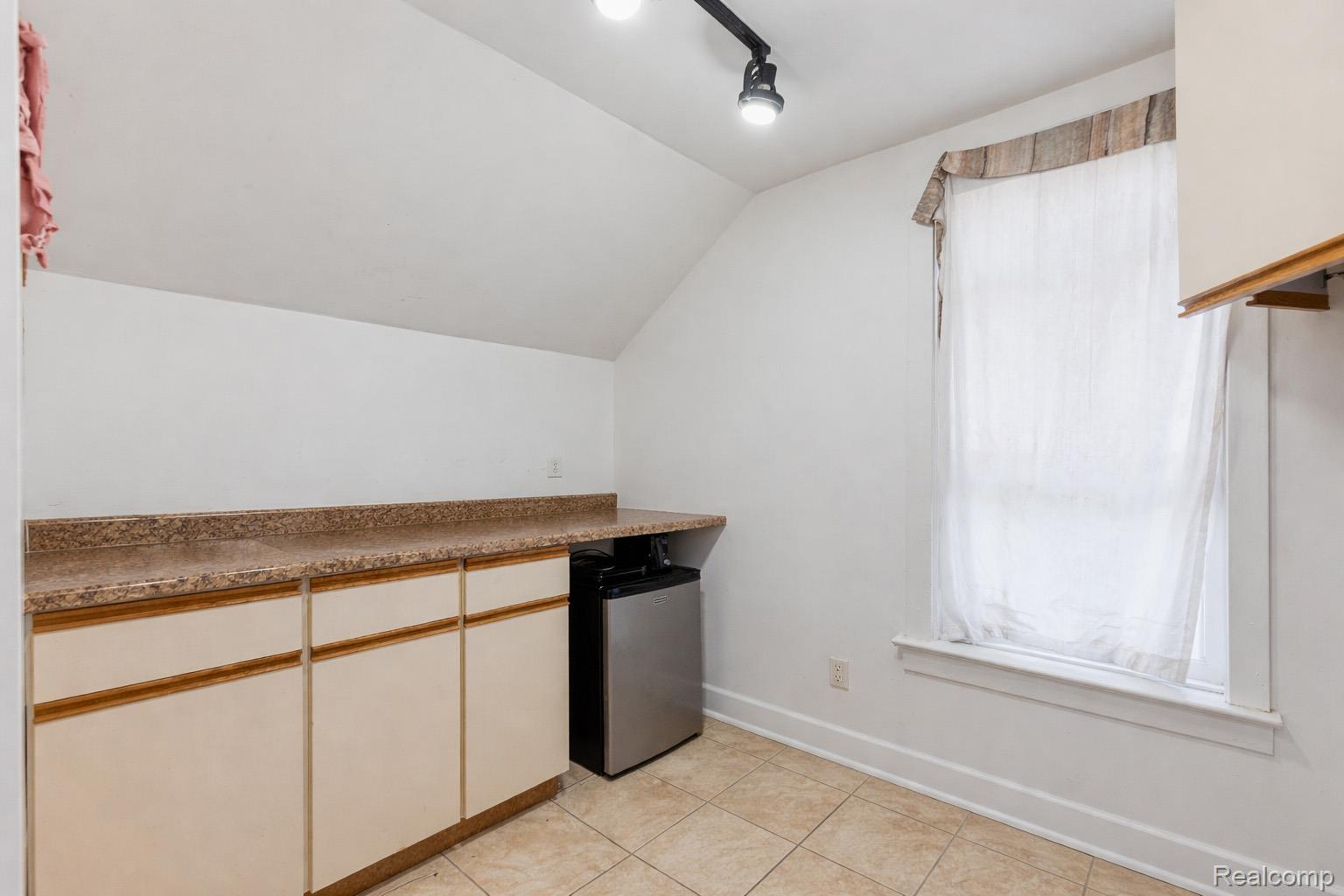 11429 East Eight Mile Road Warren, MI 48089 - Photo 11 of 23 Kitchen with lofted ceiling, stainless steel refrigerator, dark countertops, and light tile patterned floors