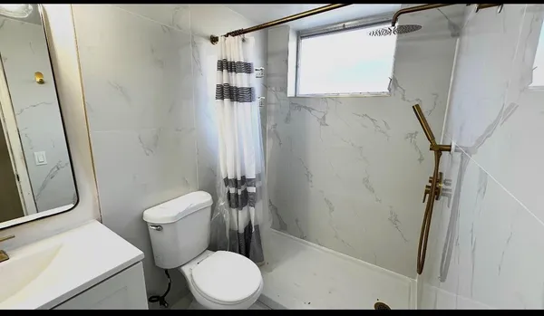 a white toilet sitting next to a shower