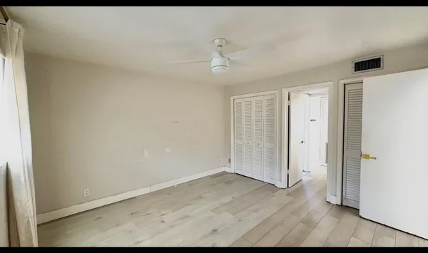 an empty room with wooden floor and ceiling fan
