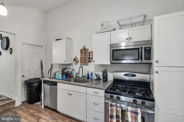 a kitchen with white cabinets a sink and a stove with wooden floor