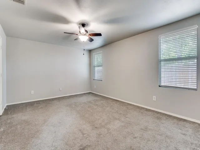 an empty room with ceiling fan and window