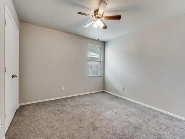 a view of an empty room and chandelier fan