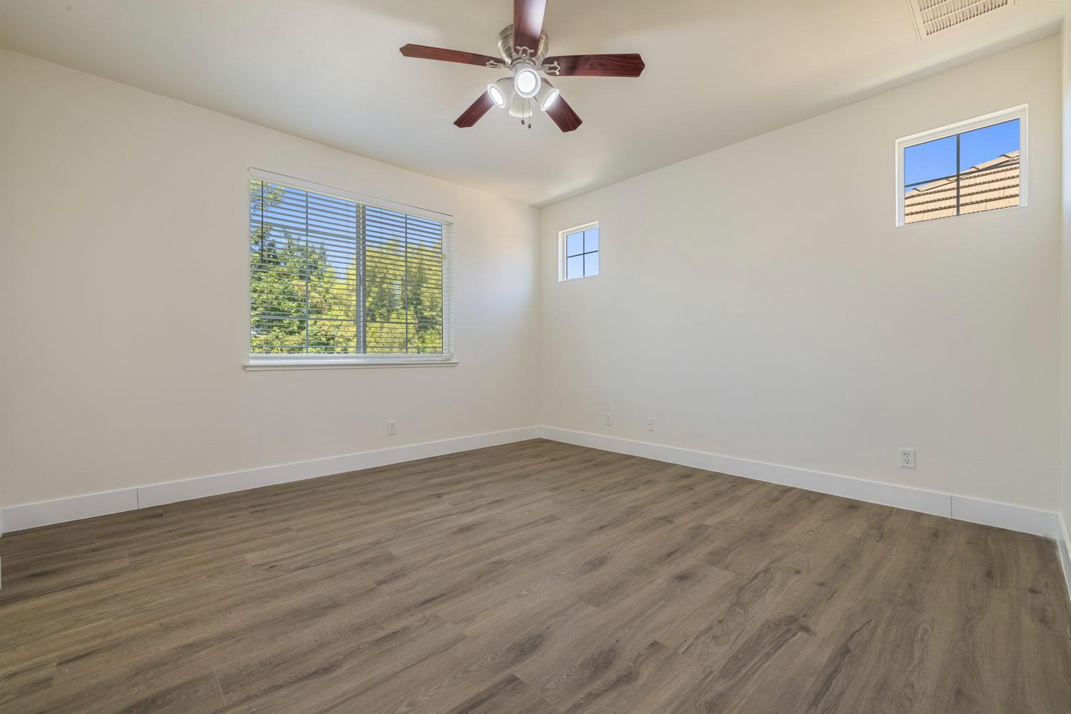 3105 Ripple Court Modesto, CA 95355 - Photo 24 of 46 an empty room with wooden floor ceiling fan and windows