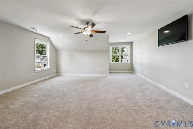 a view of a livingroom with a flat screen tv ceiling fan and windows
