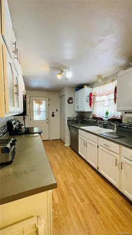 a kitchen with stainless steel appliances granite countertop a sink dishwasher stove and cabinets with wooden floor