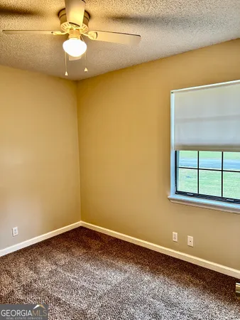 an empty room with windows and ceiling fan