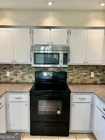 a kitchen with granite countertop a stove and a microwave