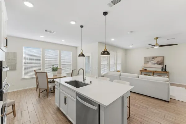 a kitchen with a sink a counter top space and living room view