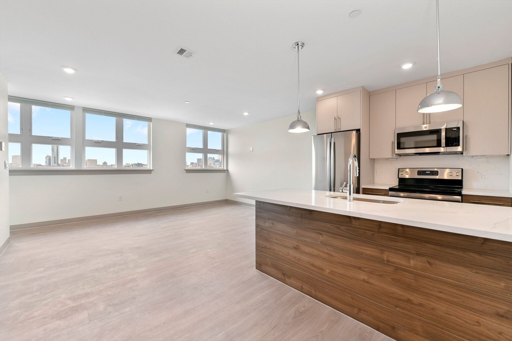 a large kitchen with stainless steel appliances a large counter top and a wooden floor