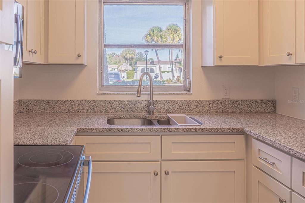 363 South McMullen Booth Road, Unit 107 Clearwater, FL 33759 - Photo 6 of 21 a kitchen with stainless steel appliances granite countertop white cabinets and a sink