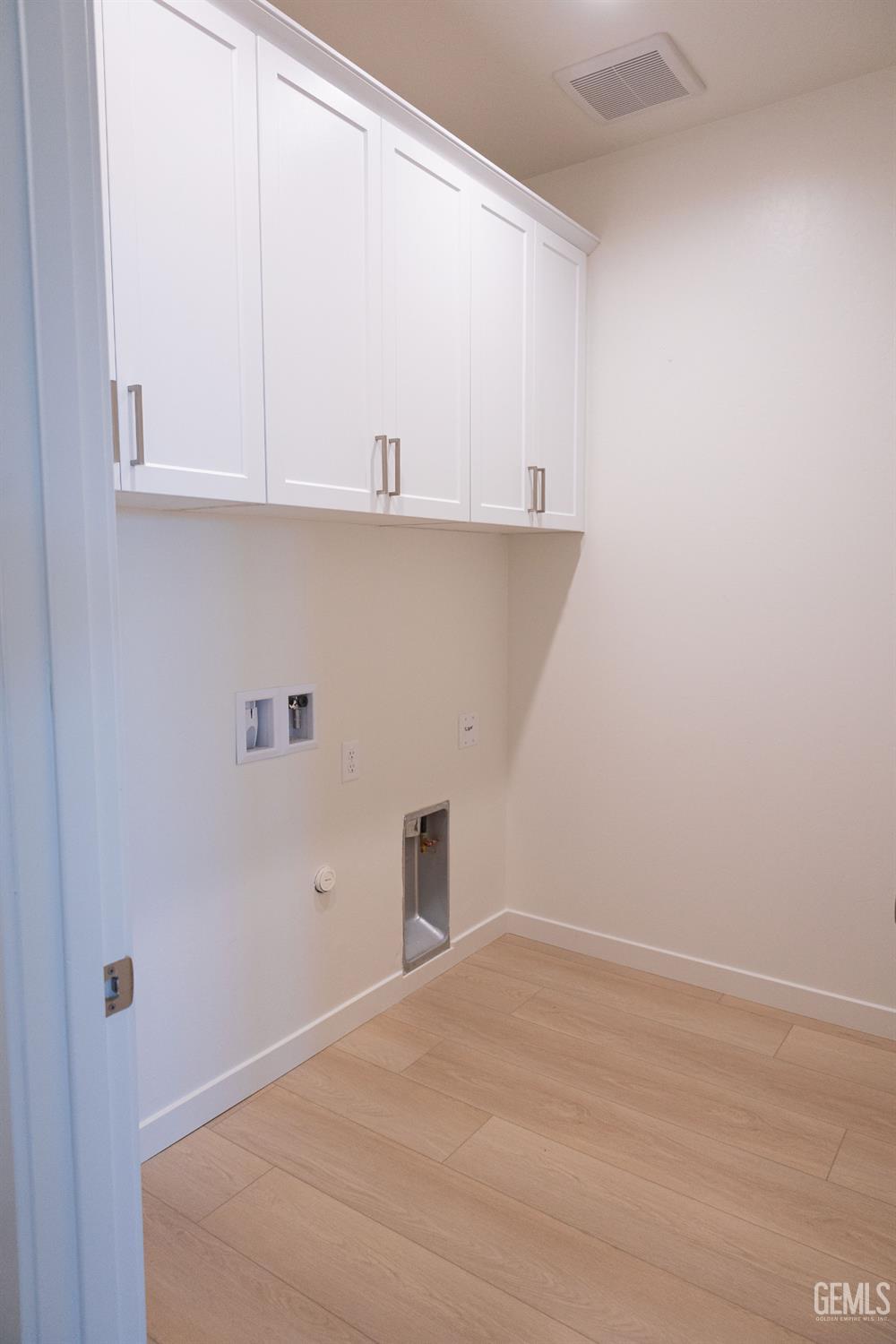 Undisclosed Address Bakersfield, CA 93311 - Photo 9 of 29 a view of a kitchen with white cabinets and a wooden floor
