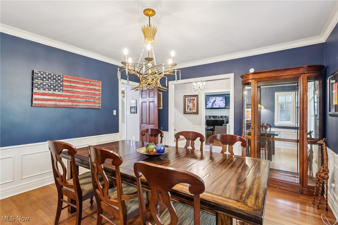 75 North Wheaton Road Akron, OH 44313 - Photo 13 of 40 Dining area with a chandelier, light wood-type flooring, a wainscoted wall, crown molding, and a decorative wall
