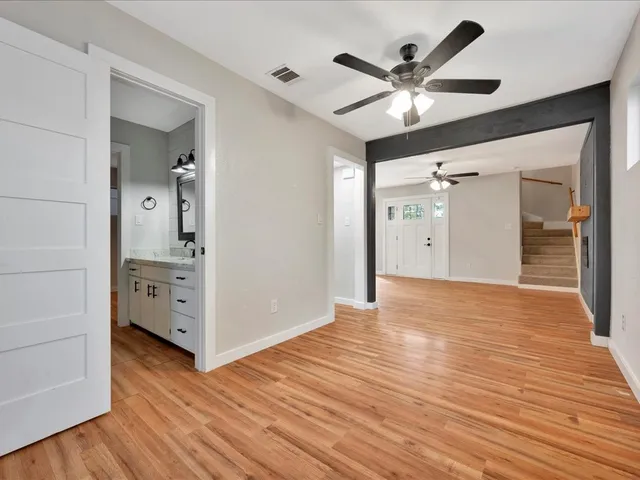 a view of empty room with wooden floor and ceiling fan