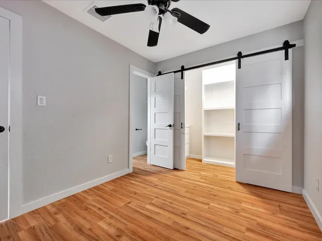 a view of empty room with wooden floor and ceiling fan