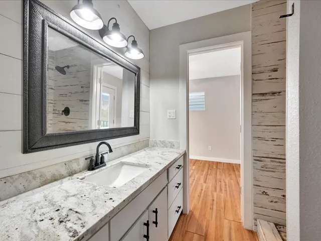 a bathroom with a granite countertop double vanity sink and mirror