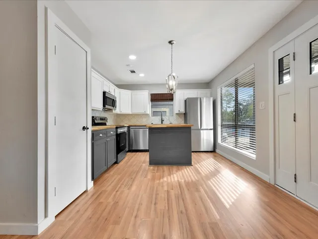 a large kitchen with stainless steel appliances kitchen island a large counter top and wooden floors