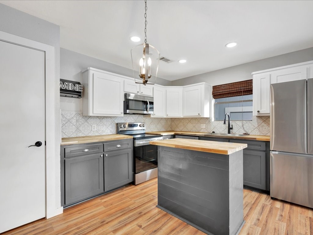 41 Harbour Row Drive Coldspring, TX 77331 - Photo 10 of 36 a kitchen with stainless steel appliances granite countertop a refrigerator a stove top oven a sink dishwasher and white cabinets with wooden floor