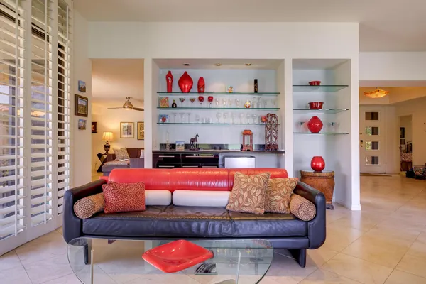 a living room with furniture a chandelier and kitchen view