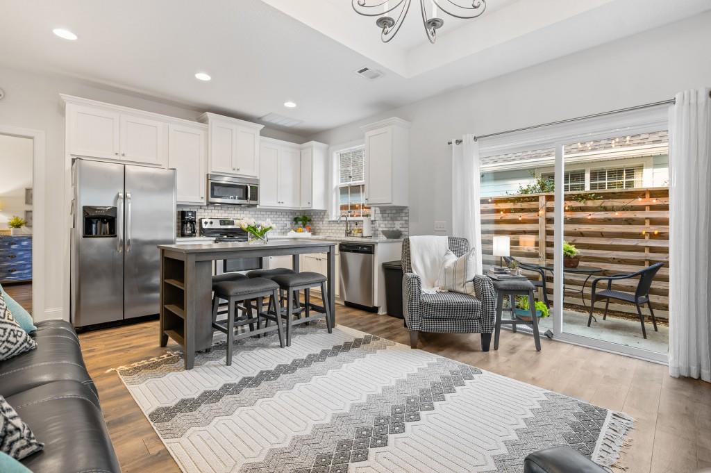 423 Palmetto Street St. Simons, GA 31522 - Photo 2 of 38 a kitchen with stainless steel appliances kitchen island granite countertop a table chairs refrigerator and sink