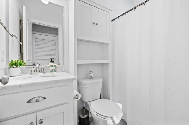 a bathroom with a granite countertop sink mirror vanity and toilet