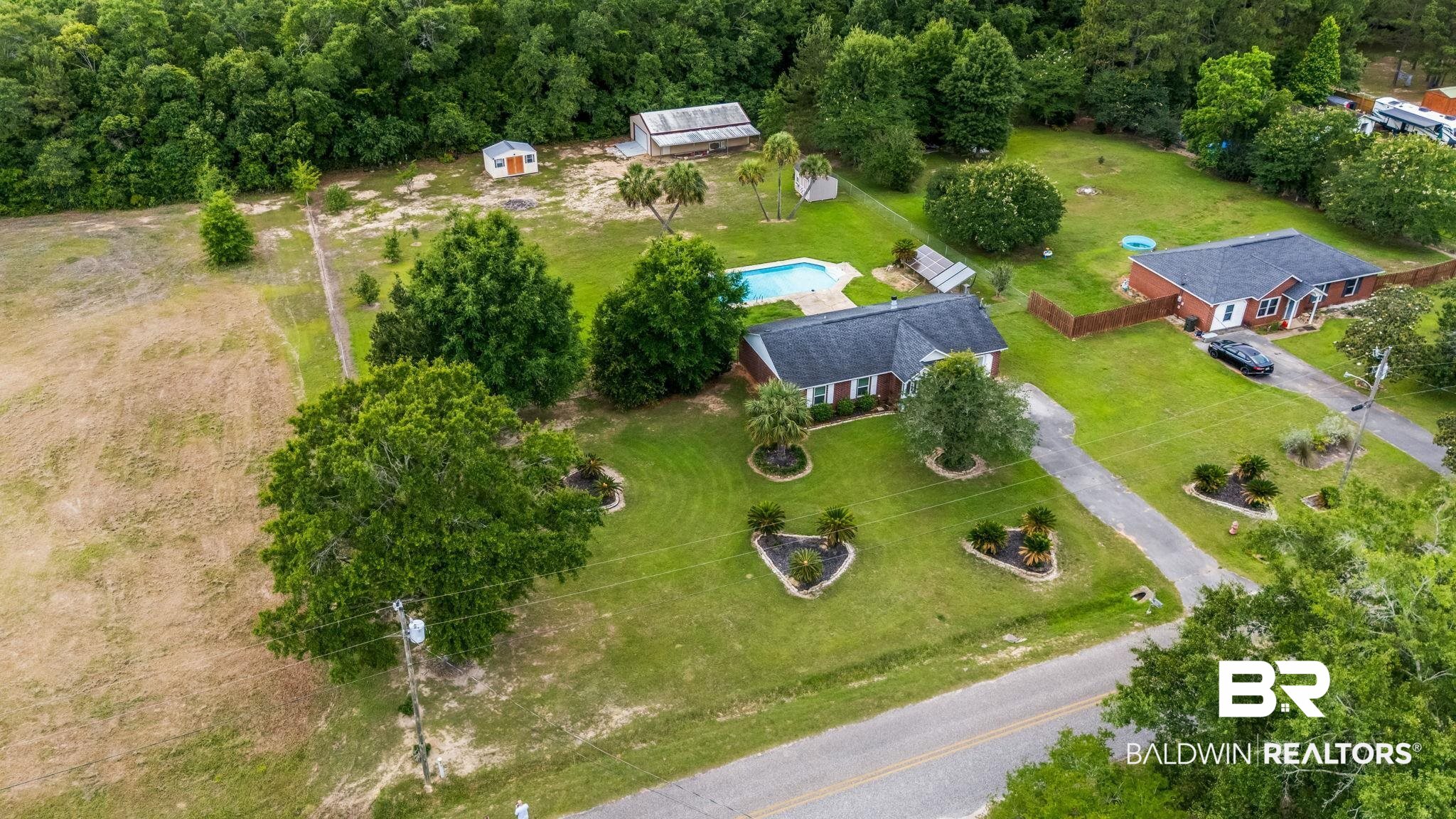 15096 Highland Circle Foley, AL 36535 - Photo 44 of 52 Expansive property featuring a single-story brick residence with a dark shingle roof, a private swimming pool, and mature landscaping
