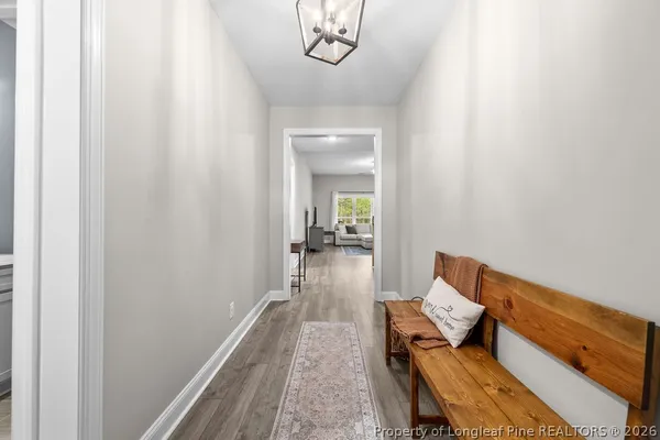 a hallway with wooden floor and a chandelier