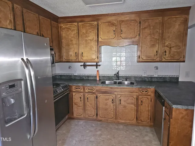 a kitchen with stainless steel appliances granite countertop a sink stove and refrigerator