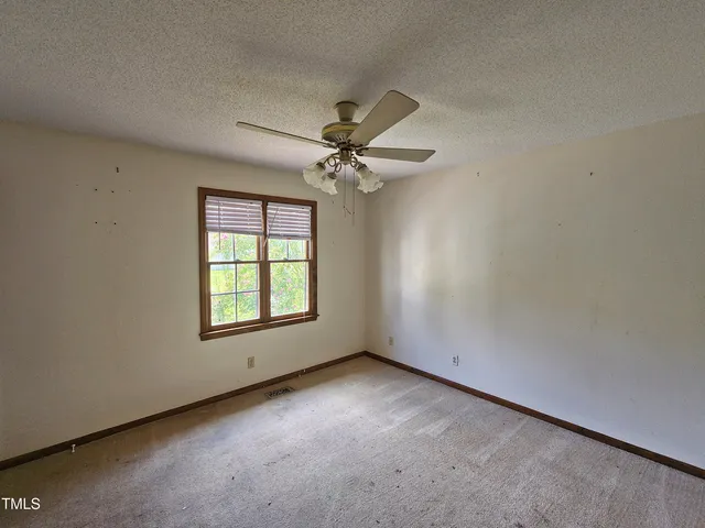 an empty room with a window and a fan