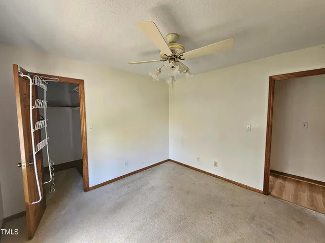 an empty room with windows and ceiling fan