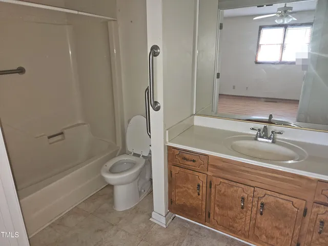 a bathroom with a granite countertop sink a toilet a mirror and shower