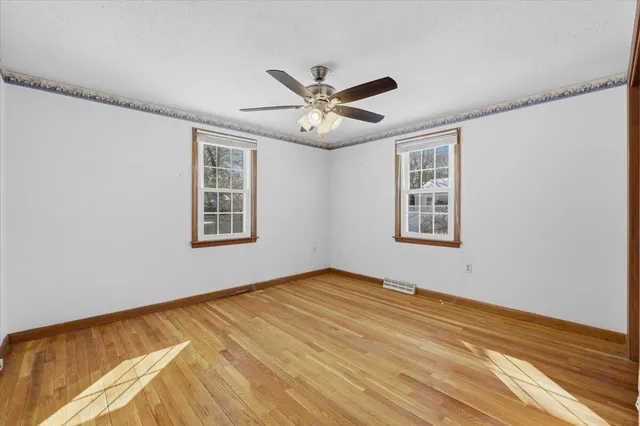 a view of an empty room with window and a ceiling fan