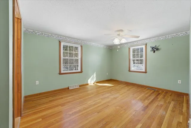 a view of an empty room with window and wooden floor