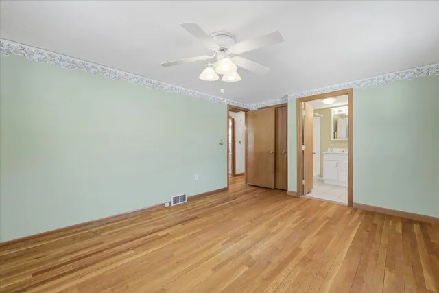 an empty room with wooden floor fan and windows