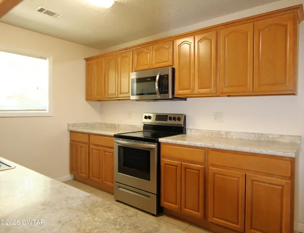 a kitchen with stainless steel appliances granite countertop a stove a sink and a microwave